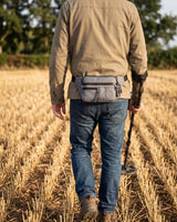 Sacoche ceinture de prospection Ordetect portée à la taille par un détectoriste vu de dos dans un champ moissonné